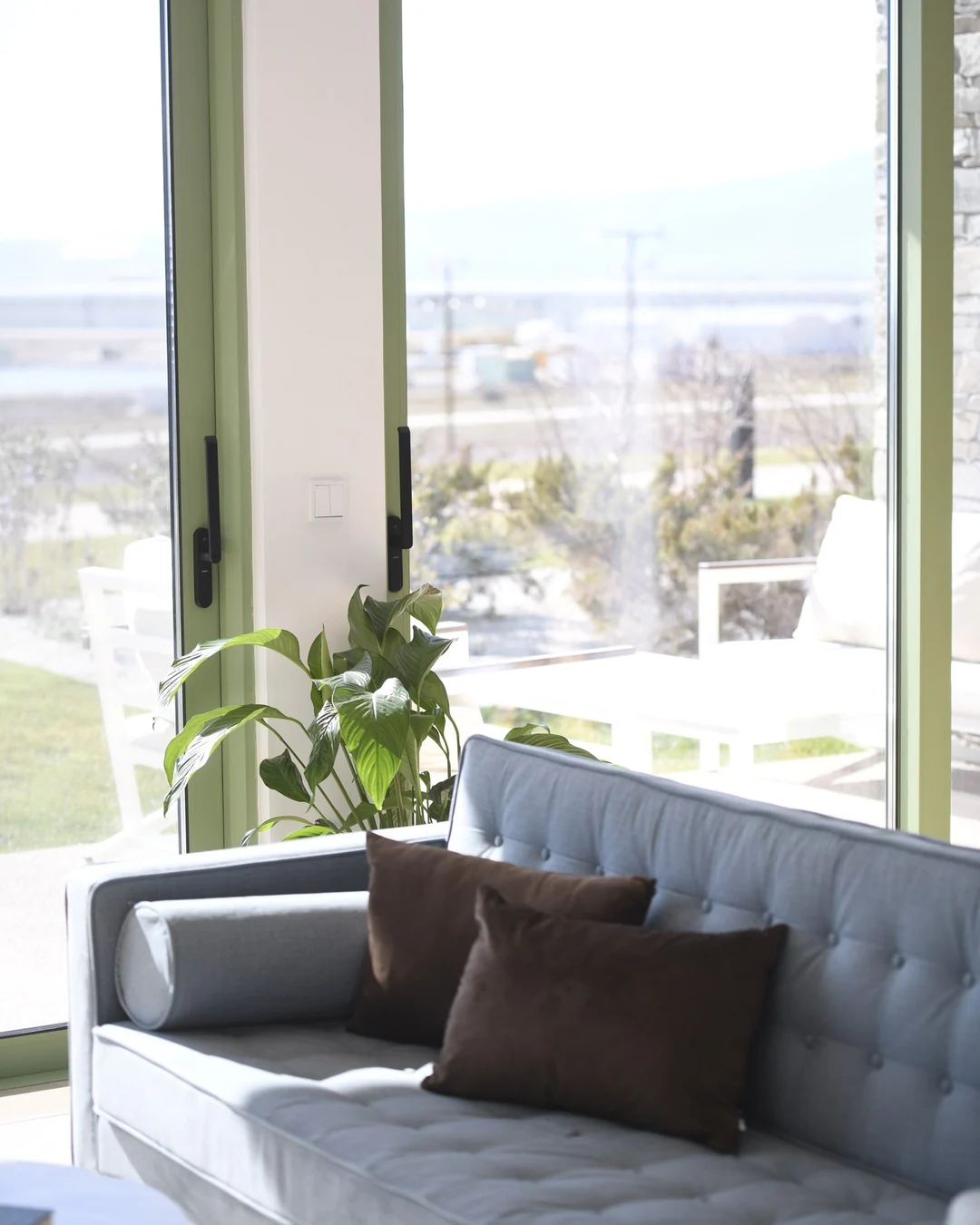 Καναπές μπροστά σε ολόσωμο άνοιγμα αλουμινίου με πράσινο πλαίσιο, με θέα στον κάμπο της Δράμας